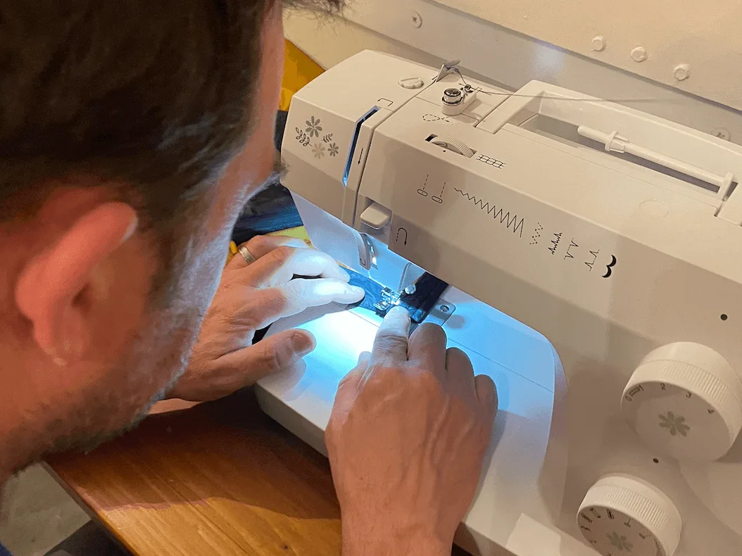 Man guiding sewing machine foot